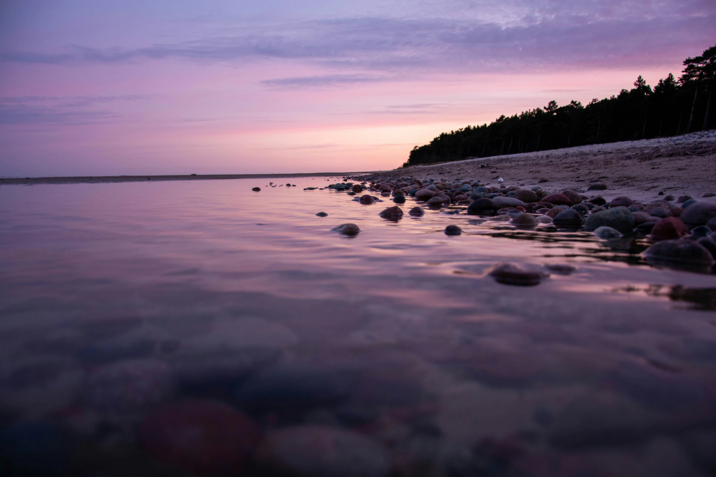 a body of water with rocks in it and a shoreline on both sides