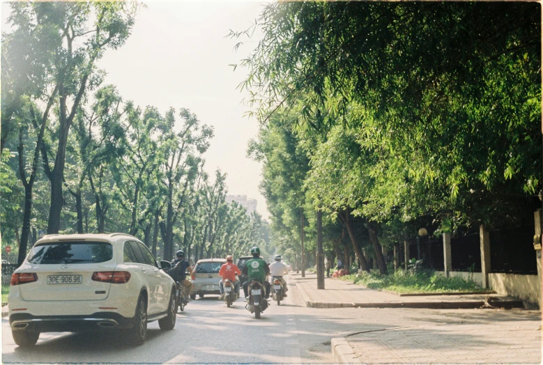 people riding motorcycles down the street and several cars