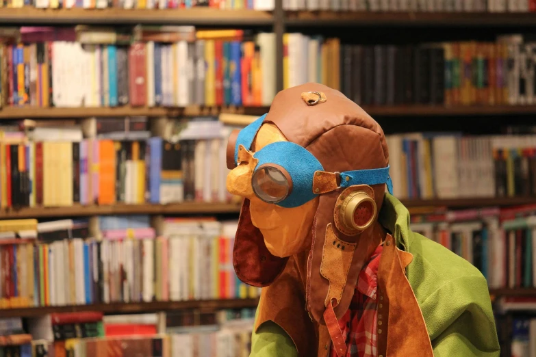 a leather helmet with goggles, sitting in front of bookshelves