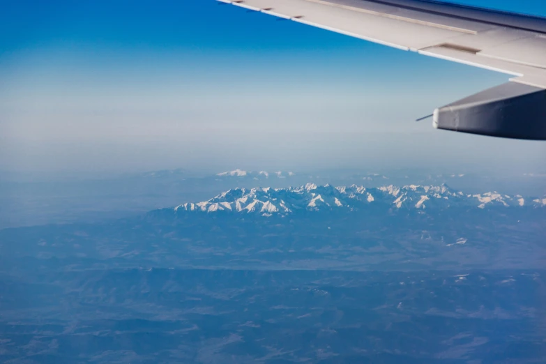 snow covered mountains are seen from a airplane window