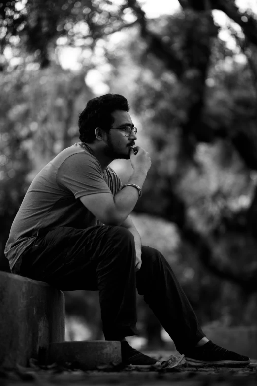 a man sitting on a wooden bench in black and white