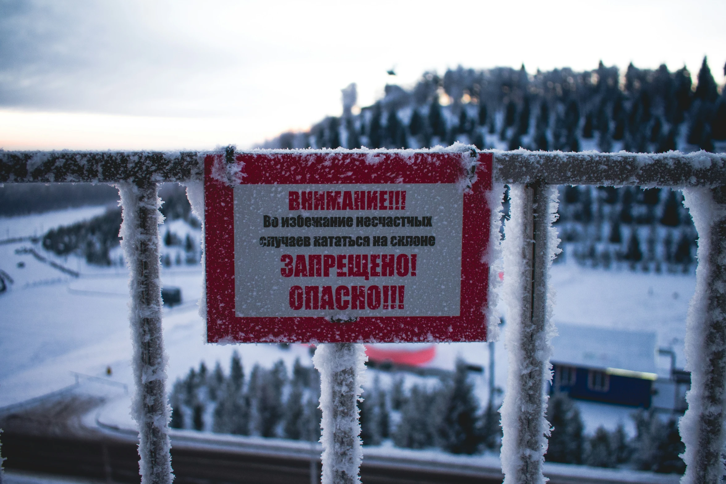 a sign posted on a gate on a snowy hill