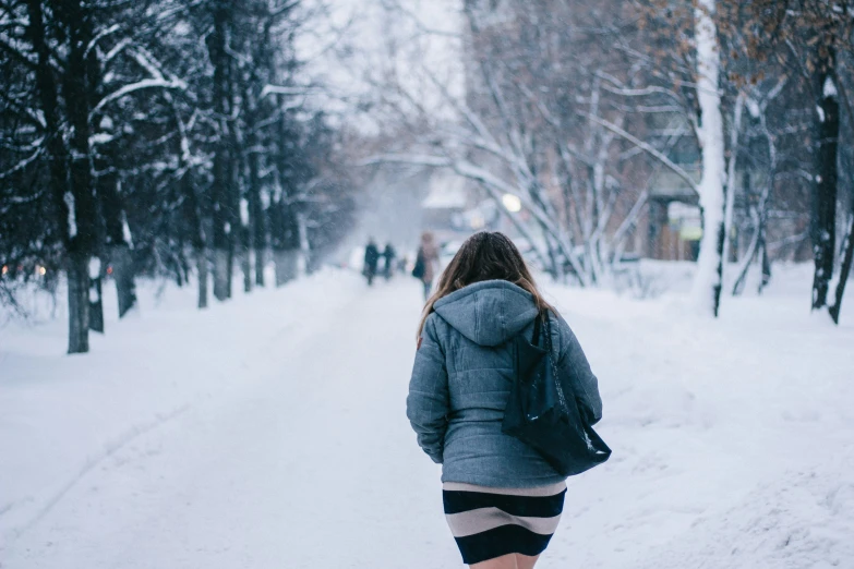 a woman with a hood and a backpack walking through the snow