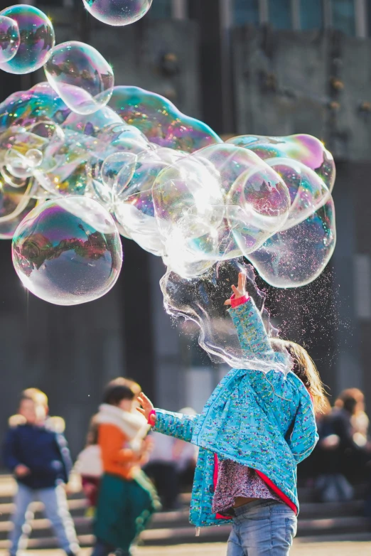 a girl playing with bubbles in front of a group of people