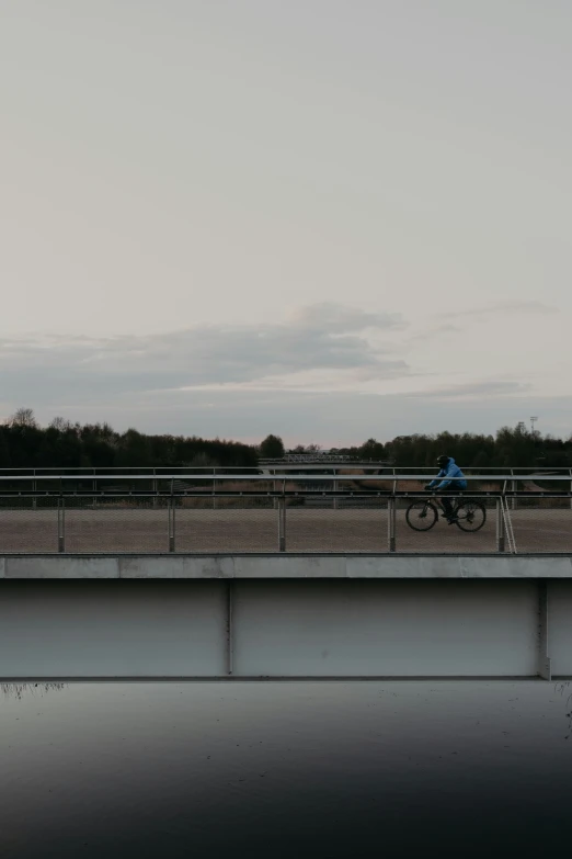 a man rides his bike over a bridge