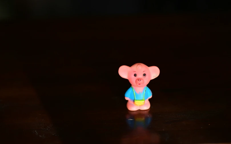 a small pink elephant toy with blue shirt