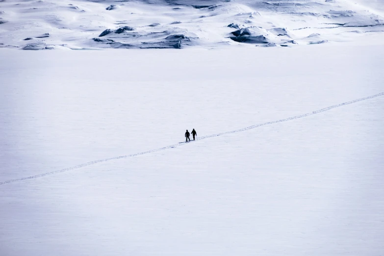two people standing on the snow in front of a mountain