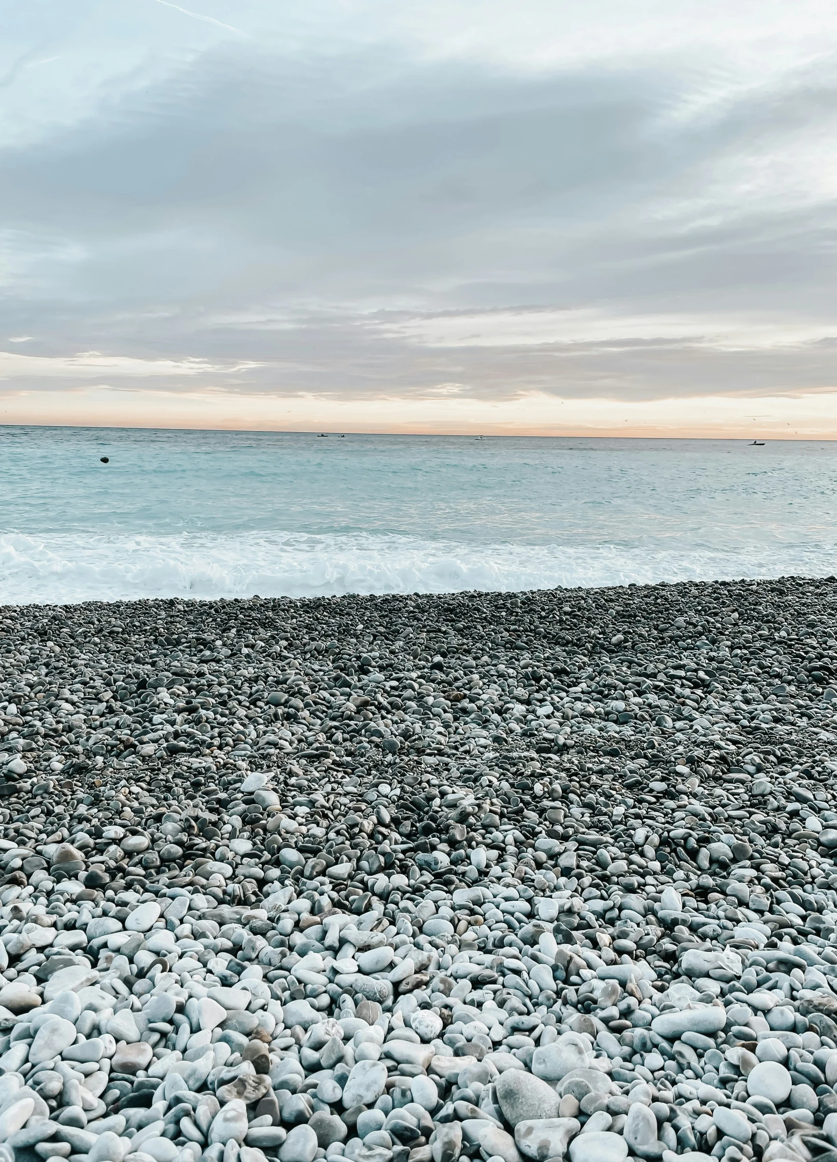 a lone surfboard sitting on a rocky beach