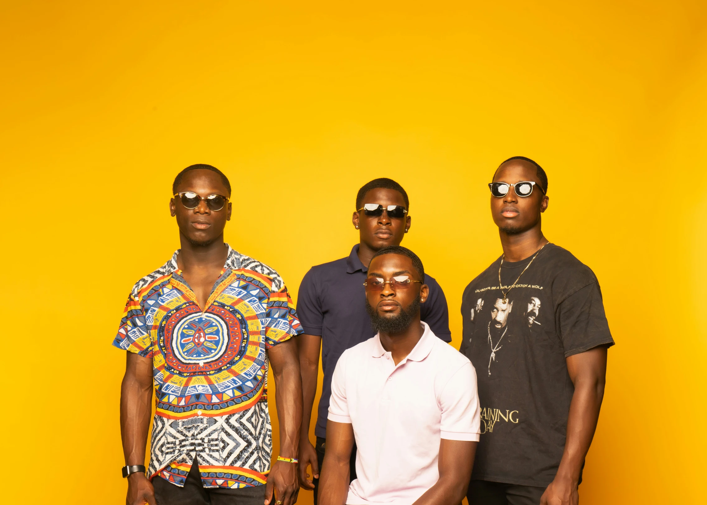 four young men pose for a pograph against a yellow backdrop