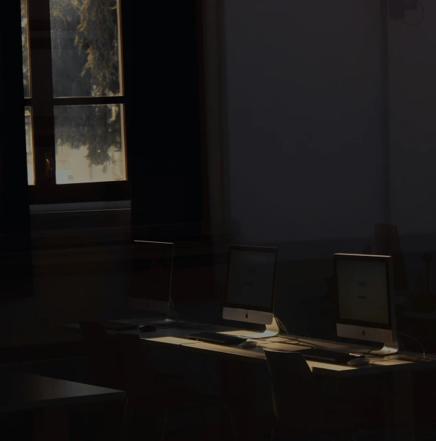 two computers sit in front of a window on a desk