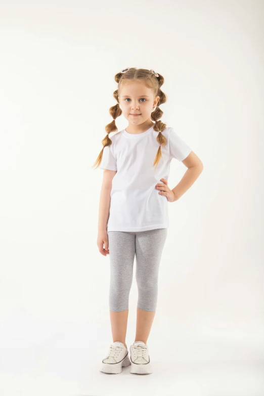 the girl is posing in a white shirt and gray pants