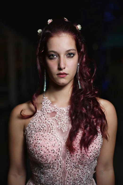 a woman with long hair wearing earrings looking straight ahead