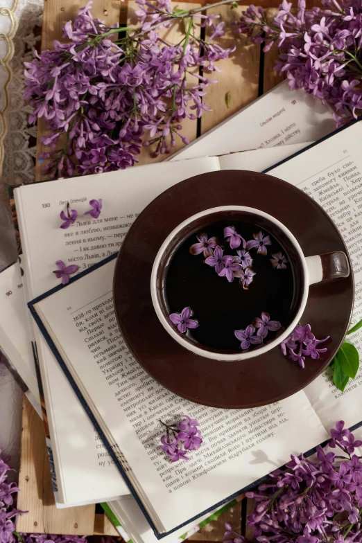 a cup of tea and some flowers next to an open book