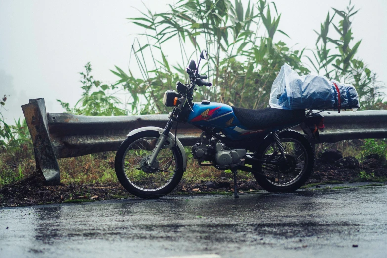 a motor cycle with an umbrella is parked in front of a wooden rail