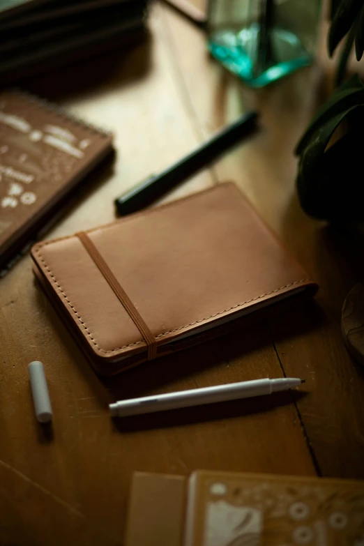 a leather notebook on the table next to a pen