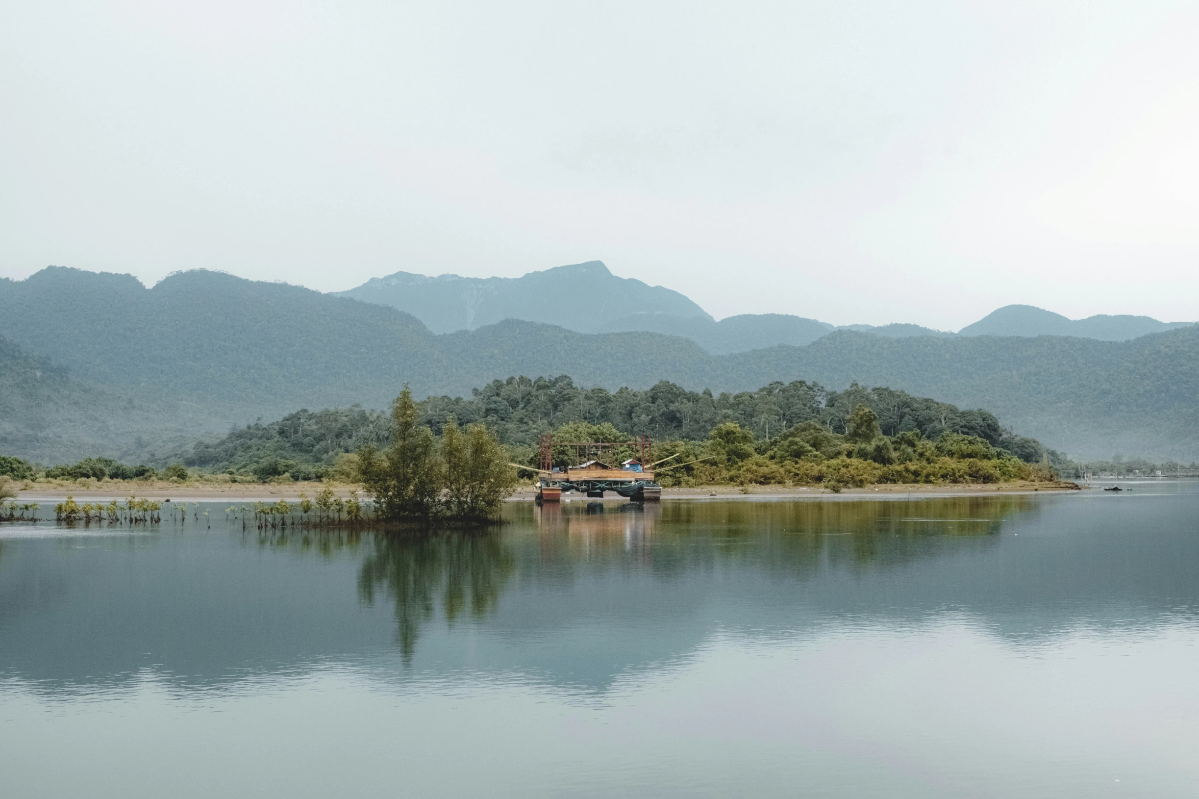 a lake surrounded by hills and trees with a small boat floating on it