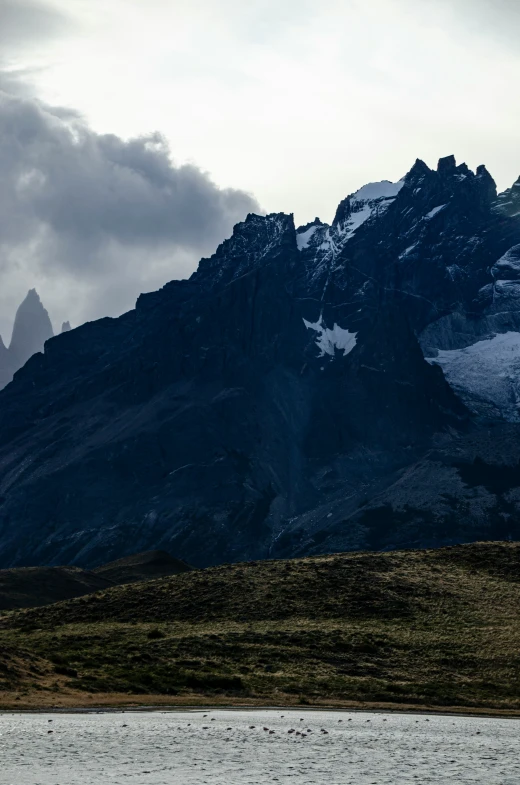 a long canoe sailing on the water in front of mountains