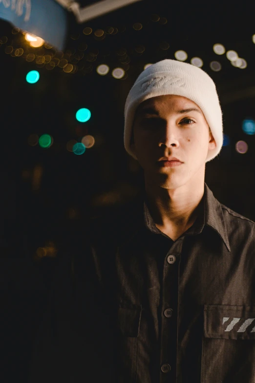 a young man standing in the street wearing a hat