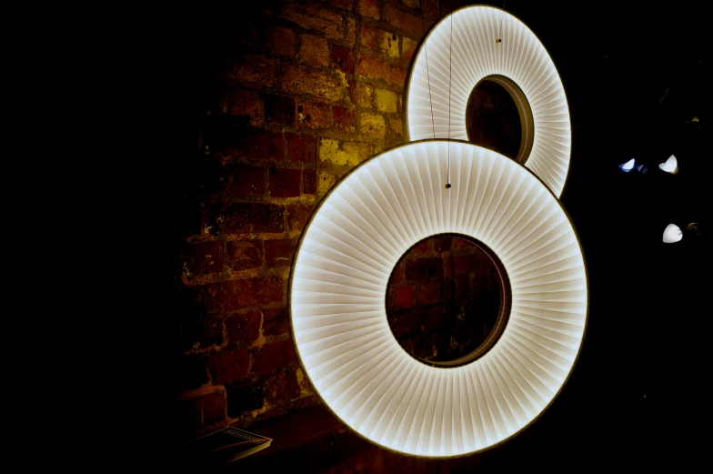 two circular light fixtures are lit up in the dark