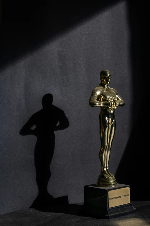 a golden statue standing next to a dark wall