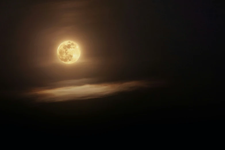 a full moon rises in the sky with clouds