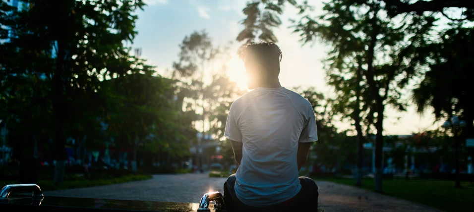 man with his suitcase at sunset sitting on a bench