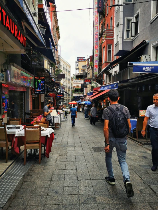 a man walking down a busy sidewalk near stores