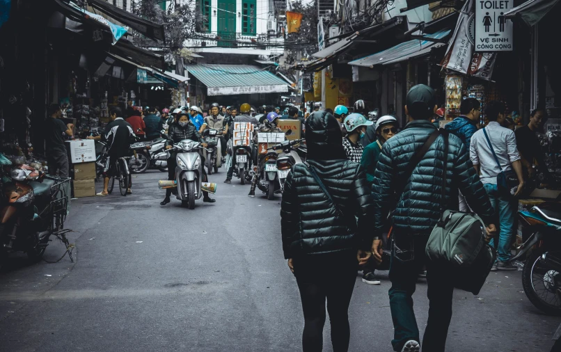 two people walk down an alley with many bikes and motorcycles