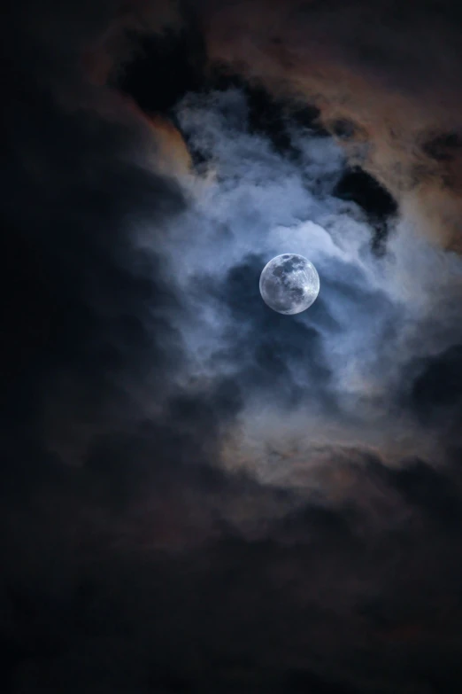 a moon shining through the clouds in a dark sky