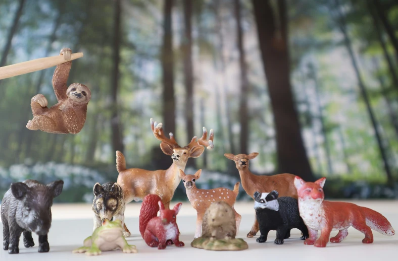 toy animals including deer, rac and fox, are arranged on a table