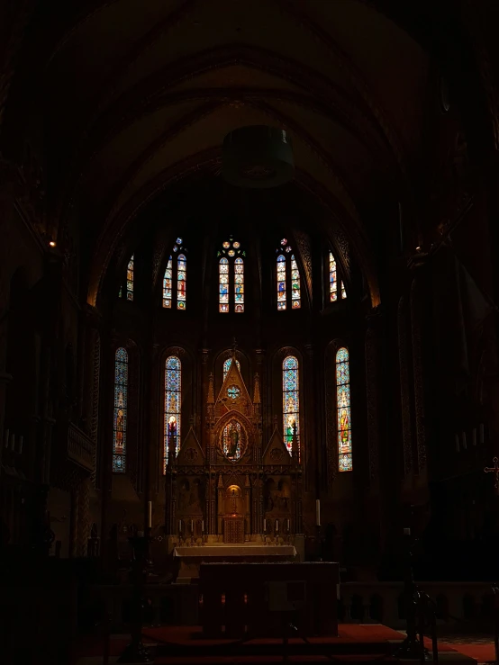 a dark church filled with pews and stained glass windows