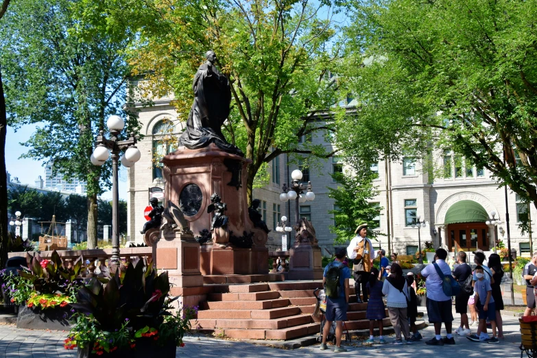 many people on the sidewalk by an outside clock