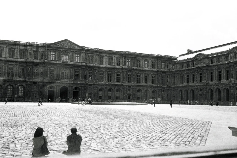 black and white image of two people sitting in front of an old building