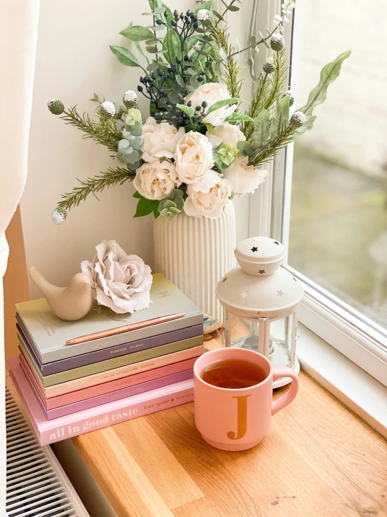 a vase of flowers and an opened book are sitting on a window sill