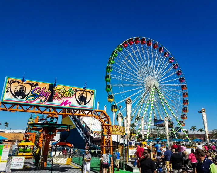 a carnival rides along with a ferris wheel and a carnival sign