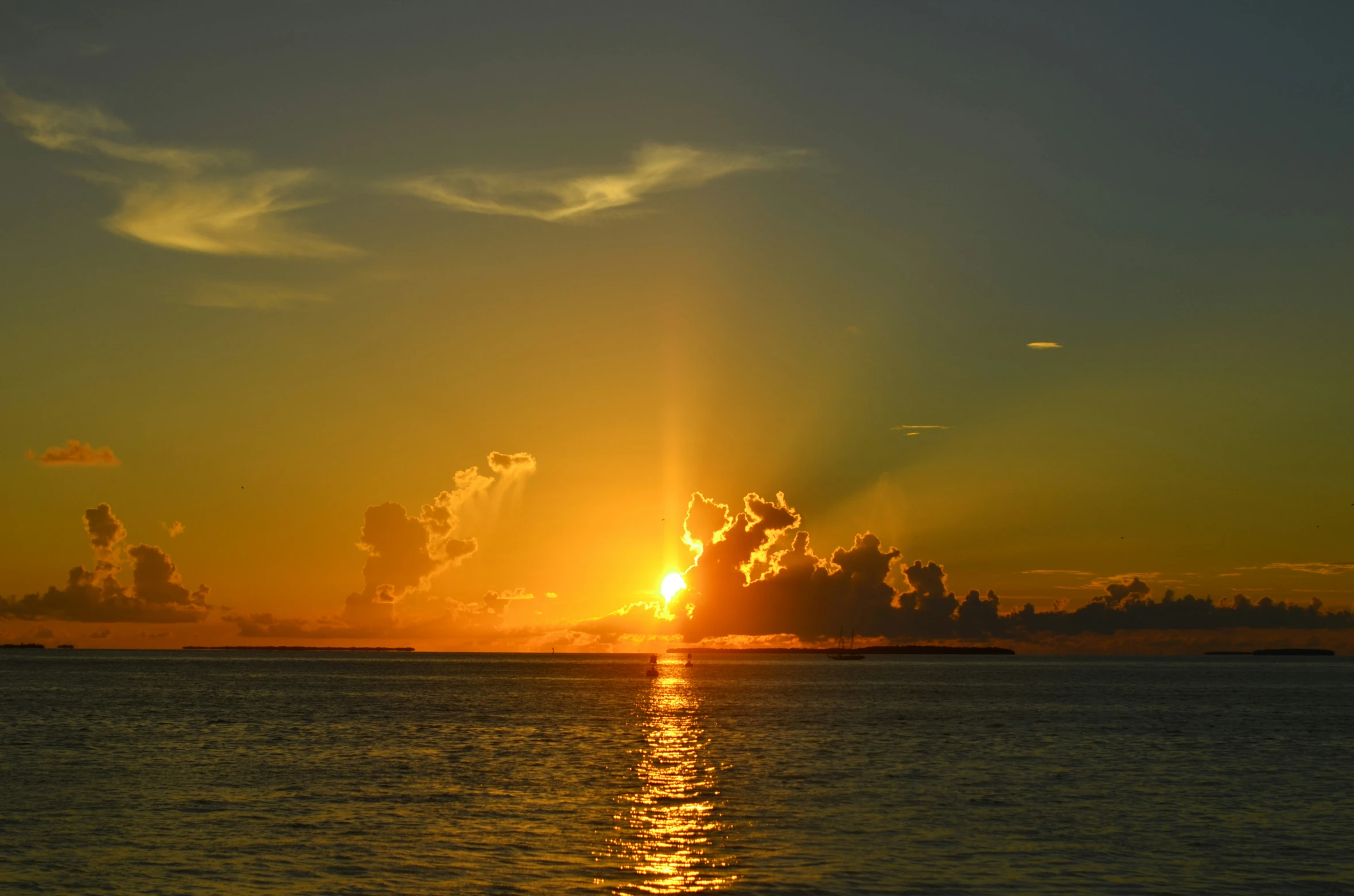 the sun is coming up over water with clouds in the sky