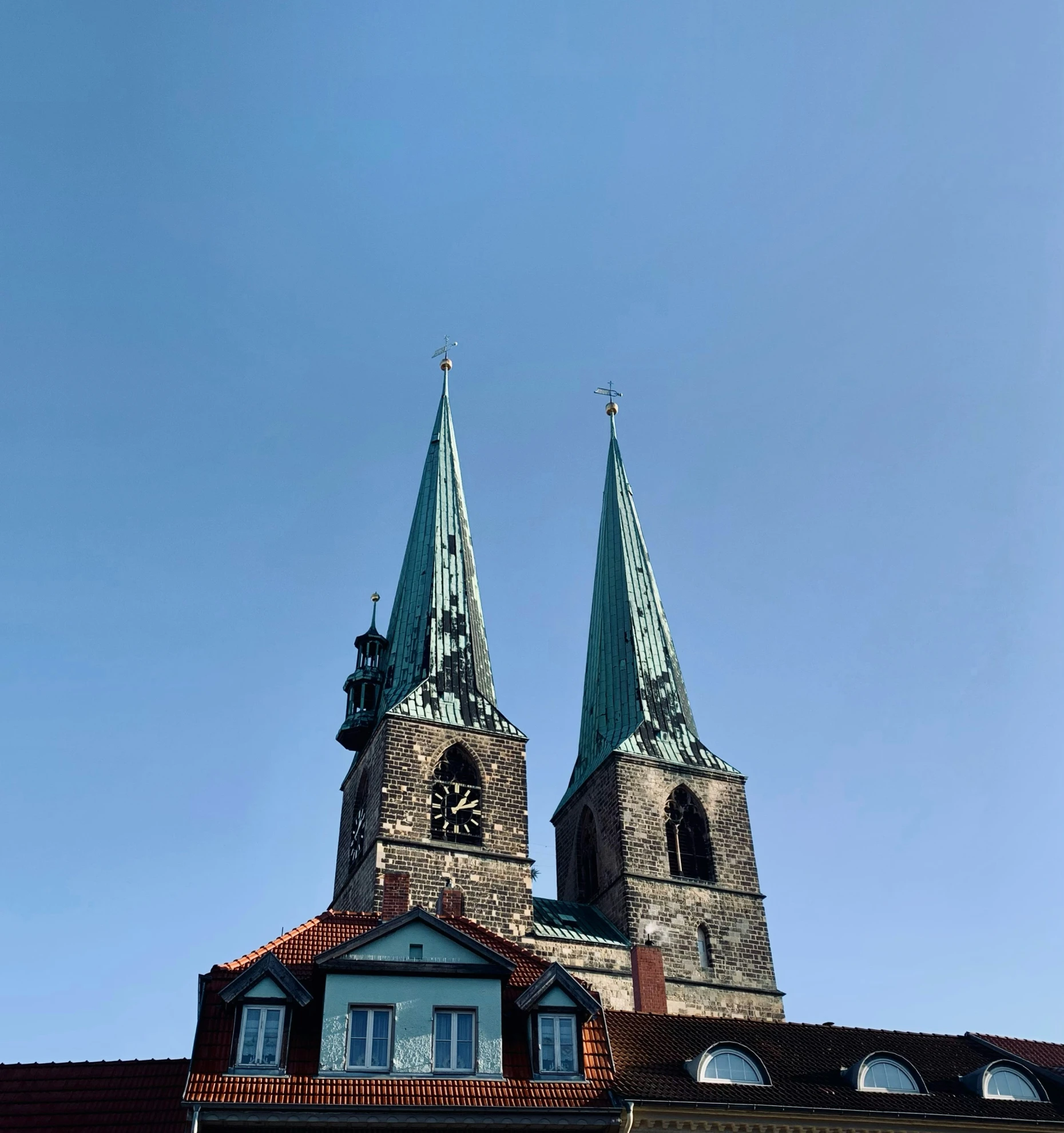 two steeples on a very tall building with a clock