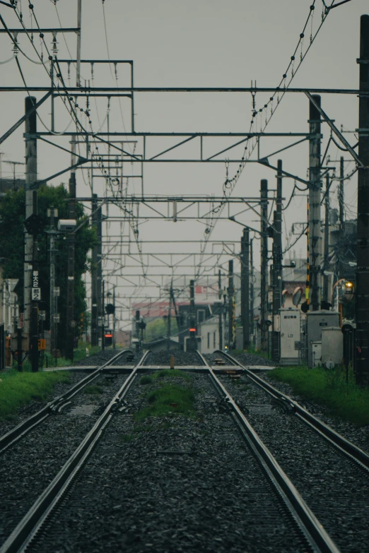 looking down the tracks at an intersection with wires running overhead