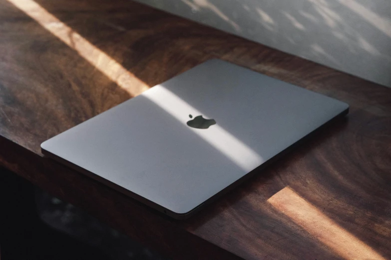 an apple laptop sitting on a wood desk