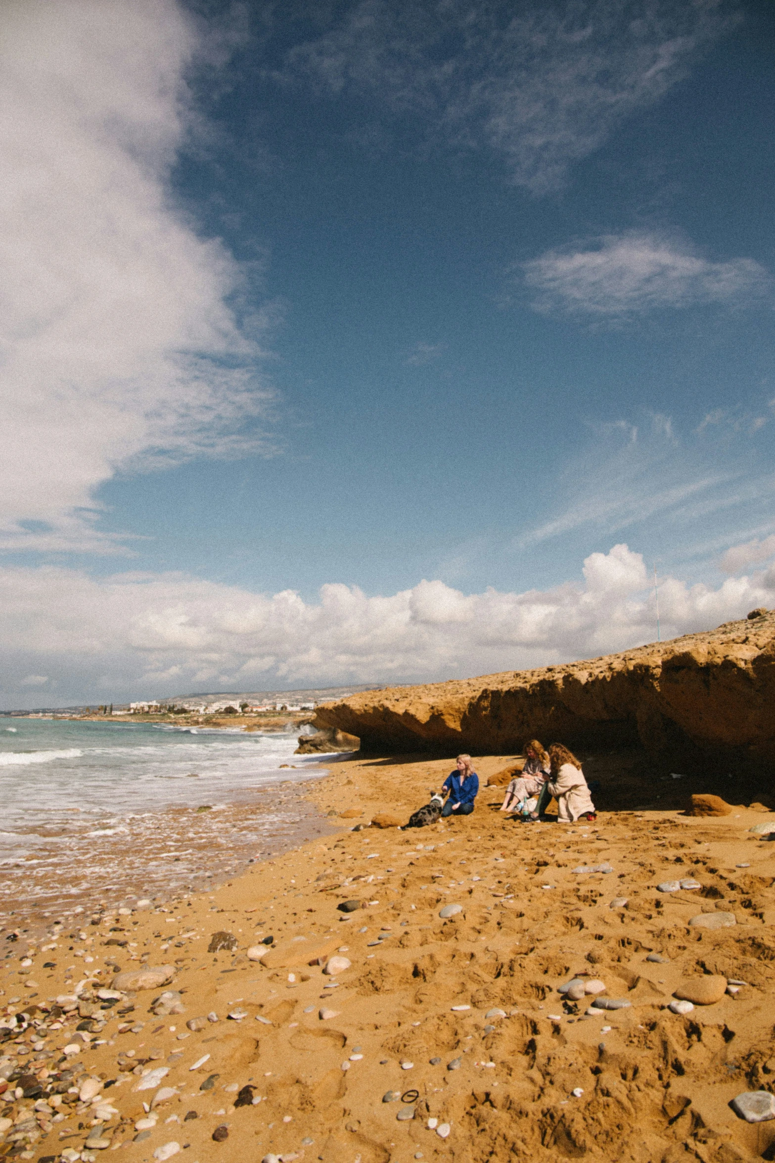 two people sitting on a sandy beach near the ocean