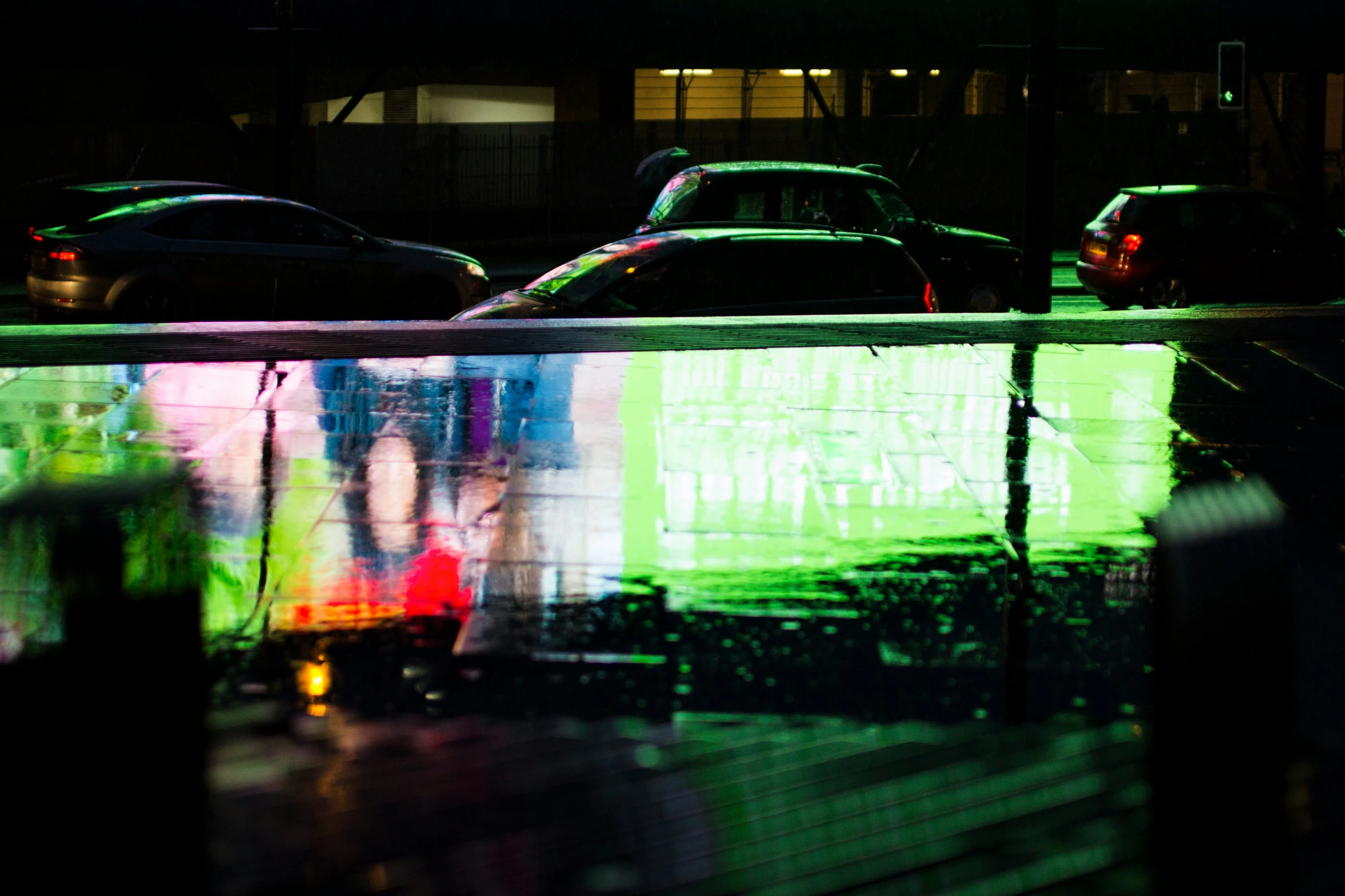 a reflection of a car parked at night and its light reflecting on the surface