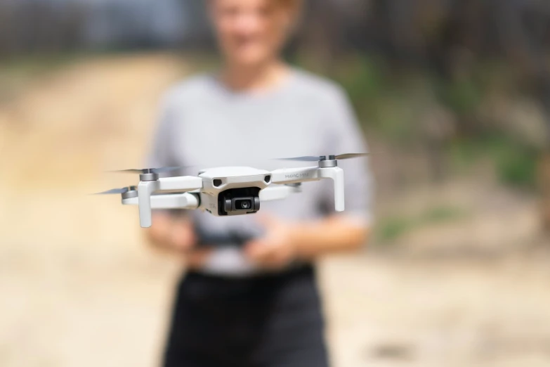 man holding up a white unmanned device in front of a camera