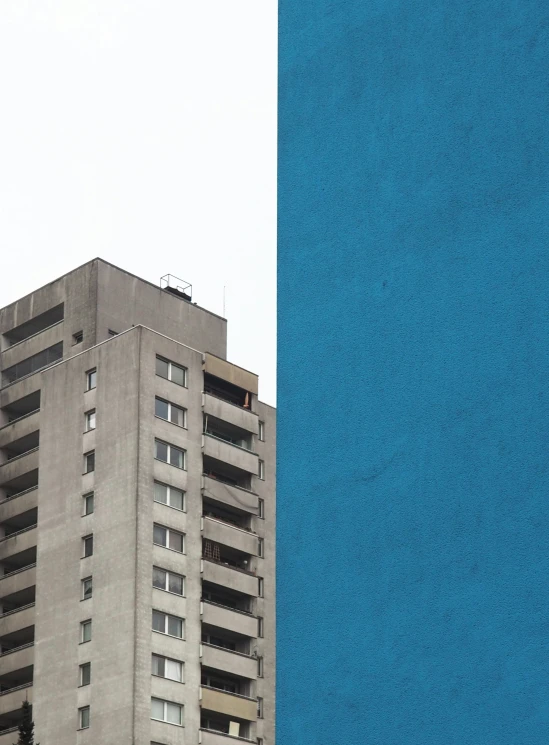 a blue building with two large windows near a tall building