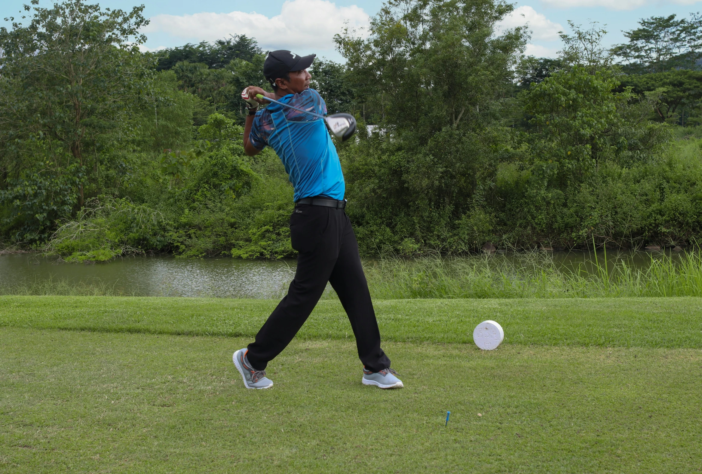 a person swings their golf club toward a white object