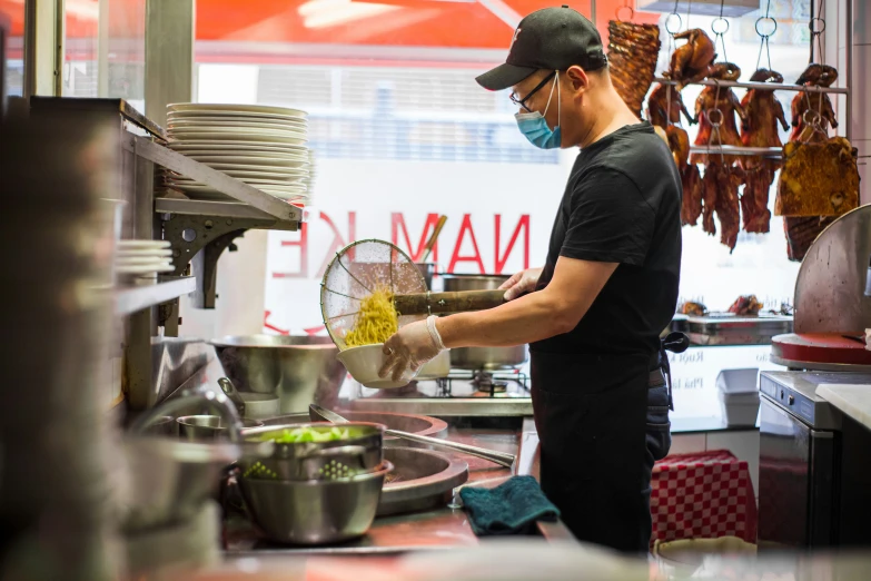 a chef prepares dinner in the kitchen with masks on