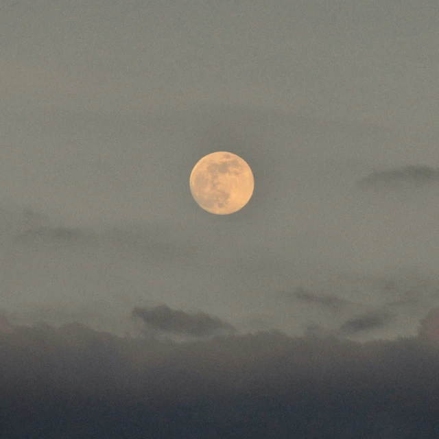 the full moon is rising behind some very cloudy clouds