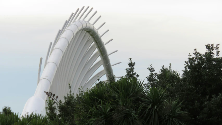 a large white sculpture in front of a tree line