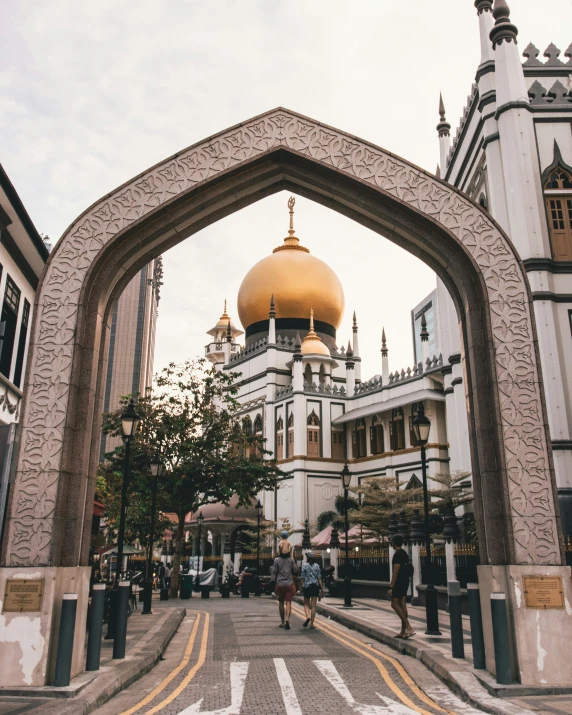 people are walking underneath the ornate arch on the street