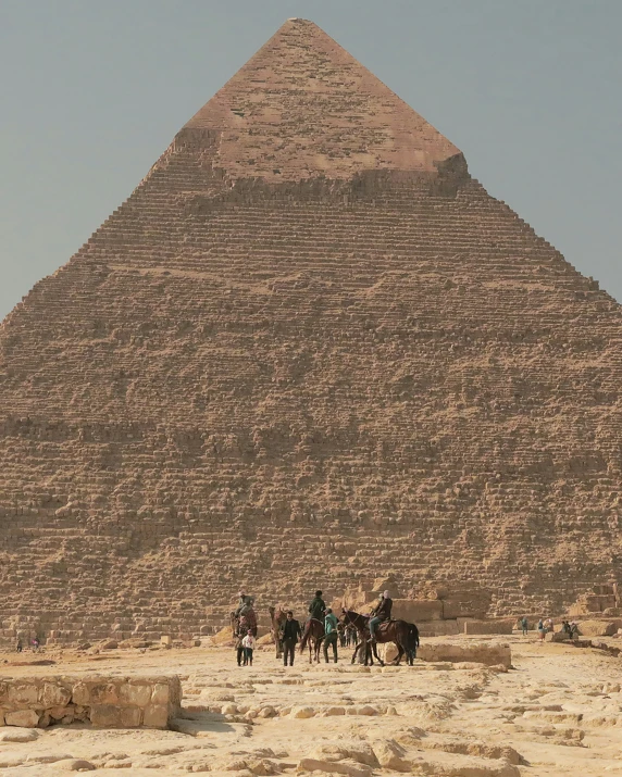 a group of people on horses in front of a pyramid