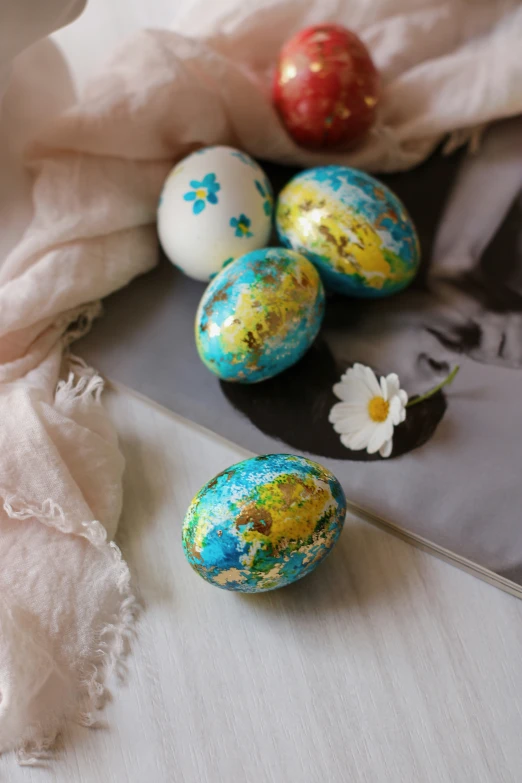 several colored eggs and flowers on a table